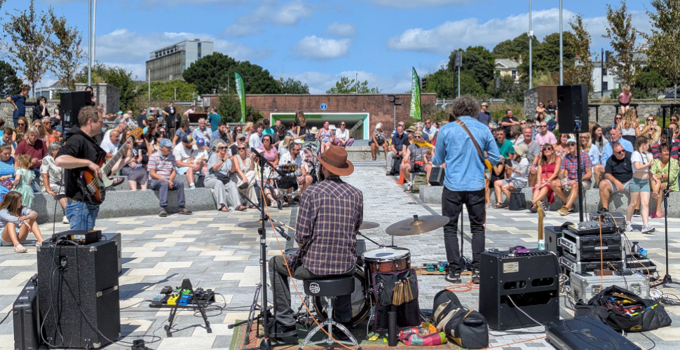 The stage to Plymouth Summer Sessions at night with members of the crowd at the front of the image